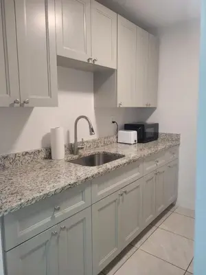 a kitchen with white cabinets and a sink at Arpe 4plex in Fort Lauderdale