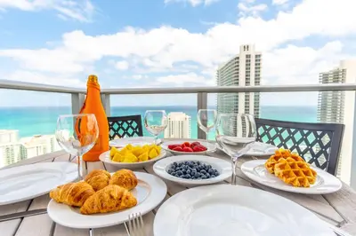 a table with plates of food and wine glasses at Amazing Pools Luxury 2Br Front Ocean Bay View in Hollywood