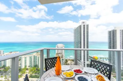 a table with plates of food on a balcony with the ocean at Amazing Pools Luxury 2Br Front Ocean Bay View in Hollywood