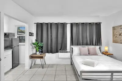 a white bedroom with a bed and a kitchen at Executive Studio Suite Hollywood Beach Blvd in Hollywood