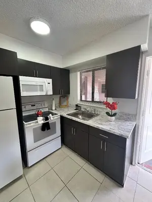 a kitchen with black cabinets and a white appliance at Apartment in Hollywood close to shops & beach 110 in Hollywood
