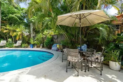 a table and chairs with an umbrella next to a pool at Charming Cottage 1BR, Pool, Victoria Park in Fort Lauderdale