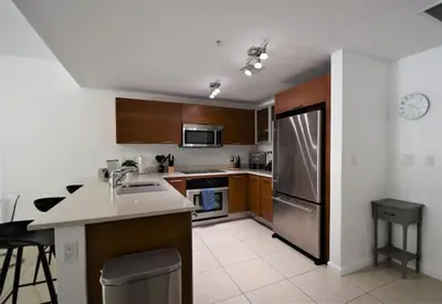 a kitchen with wooden cabinets and a stainless steel refrigerator at Lovely Midblock building 1 bedroom 1 bathroom apartment in Miami