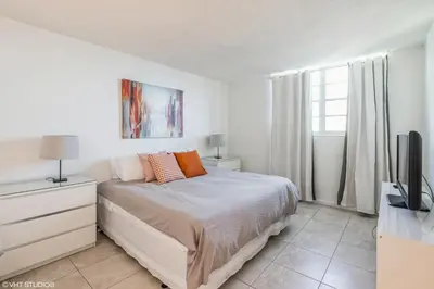 a white bedroom with a bed and a tv at Tides building over the beach apartments in Hollywood