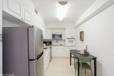 a kitchen with a refrigerator and a table with chairs at Tides building over the beach apartments in Hollywood