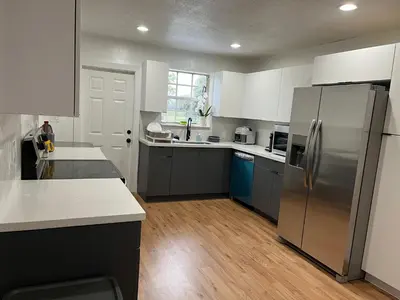 a kitchen with a stainless steel refrigerator and white cabinets at Edercozy in Miami