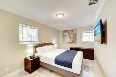 a bedroom with a large bed and a nightstand with a bed sidx sidx sidx at Tropical Oasis 6BR & 4BR Villa Heated Pool & Billiard Room in Hollywood
