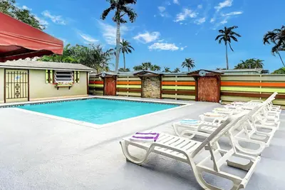a swimming pool with lounge chairs next to a house at Tropical Oasis 6BR & 4BR Villa Heated Pool & Billiard Room in Hollywood