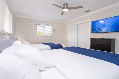 a white bedroom with two beds and a flat screen tv at Amazing 5BR Villa Heated Pool near Hard Rock in Hollywood