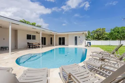 a swimming pool with chairs and a table at Amazing 5BR Villa Heated Pool near Hard Rock in Hollywood