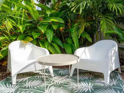 two white chairs and a table in front of plants at New Nordic Touch Loft, Central Location in Miami