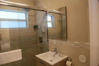 a bathroom with a sink and a shower with a mirror at Diane Oceanfront Suites in Hollywood