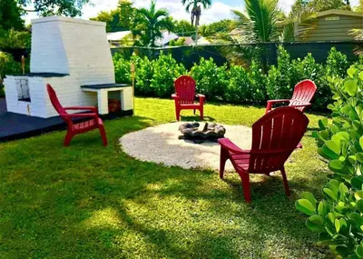 four red chairs and a fire pit in a yard at Charming house Miami in Miami