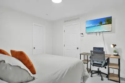 a bedroom with a bed and a desk with a tv on the wall at Suite Azul Miami - Private Guest Suite with Patio, Free Parking, Near Wynwood and Beaches in Miami