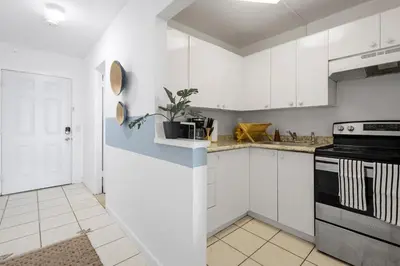 a kitchen with white cabinets and a black stove at Bayshore Bliss, Cozy with Water Views of Miami Bay in Miami Beach