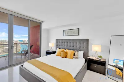 a bedroom with a large bed and a balcony at Breathtaking 31st Fl Beachwalk Penthouse View in Hallandale Beach