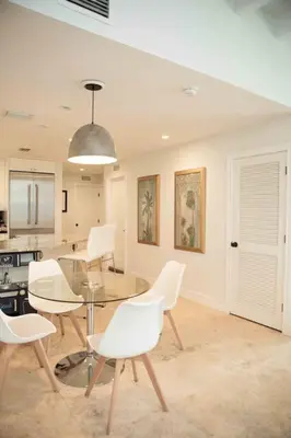 a dining room with a glass table and white chairs at Pool! Best location! Steps to the water! Kid friendly! in Miami