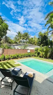 a swimming pool with two chairs and a table next to it at Pool! Best location! Steps to the water! Kid friendly! in Miami
