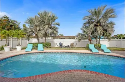 a swimming pool with chairs and palm trees at Modern 4 Bedroom -Kosher - Heated Pool - Game Room in Hollywood