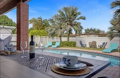a table with a bottle of wine and glasses next to a pool at Modern 4 Bedroom -Kosher - Heated Pool - Game Room in Hollywood