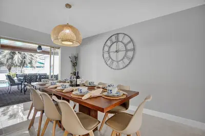 a dining room with a table and chairs and a clock at Modern 4 Bedroom -Kosher - Heated Pool - Game Room in Hollywood