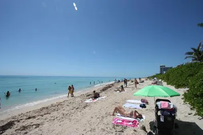 a group of people on a beach with an umbrella at Miami Beach Apartments by MiaRentals in Miami Beach