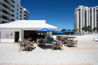 a group of tables and chairs with blue umbrellas at Miami Beach Apartments by MiaRentals in Miami Beach