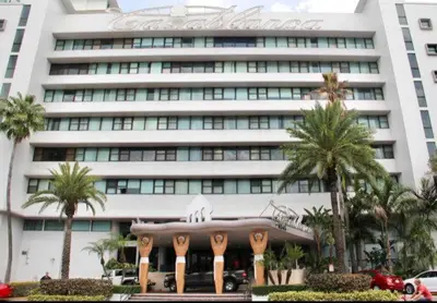 a large white building with palm trees in front of it at Oceanfront Miami Beach Studio 925 in Miami Beach