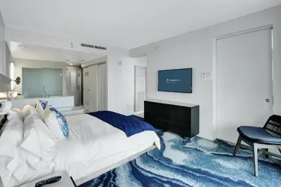 a bedroom with a large bed and a tv on a wall at Nautica - Ocean View & Rooftop Pools! by Newman Hospitality in Fort Lauderdale