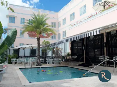 a pool in front of a building with a palm tree at Roami at Hotel Astor in Miami Beach