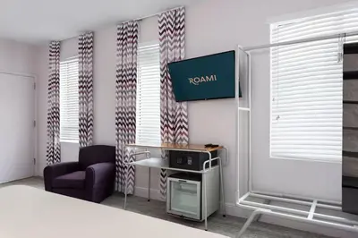 a room with a bed and a chair and a tv at Roami at Hotel Astor in Miami Beach