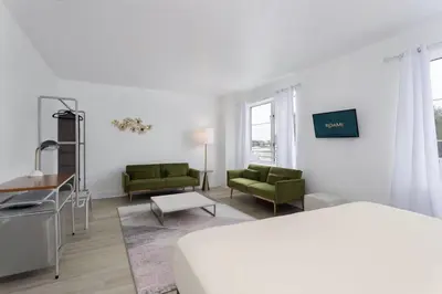 a white room with a bed and two green chairs at Roami at Hotel Astor in Miami Beach