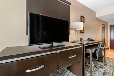a hotel room with a desk with a large television at Comfort Suites Fort Lauderdale Airport South & Cruise Port in Dania Beach