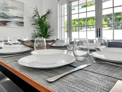 a wooden table with white plates and glasses on it at Gated Villa Blanca 5BR 3BA with Heated Pool & BBQ in Miami