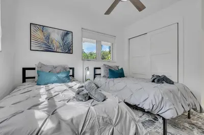 two beds in a white room with blue pillows at Gated Villa Blanca 5BR 3BA with Heated Pool & BBQ in Miami