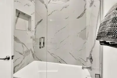 a bathroom with a shower with a white tub at Ocean Wave Deluxe Brand New Apartments in Fort Lauderdale