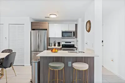 a kitchen with a counter with stools and a refrigerator at Modern apartment in Edgewater in Miami