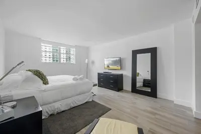 a white bedroom with a bed and a mirror at Spacious apartment of 2BR - 2BTH in Ocean Reserv front the beach in Sunny Isles Beach