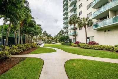a walkway in front of a building with palm trees at Spacious apartment of 2BR - 2BTH in Ocean Reserv front the beach in Sunny Isles Beach