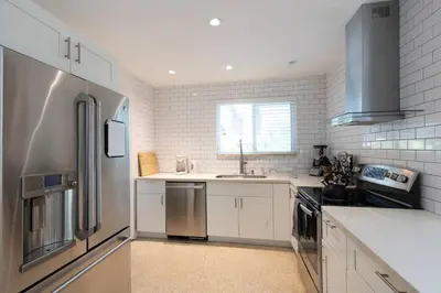 a kitchen with white cabinets and a stainless steel refrigerator at Tropical Private Oasis Mins from Beach & Downtown in Miami