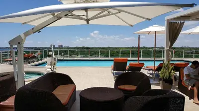 a patio with chairs and an umbrella and a pool at Coconut Grove Gorgeous Bay View 1 bedroom Condo Includes Parking in Miami