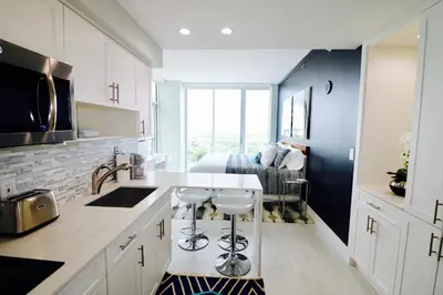 a kitchen with white cabinets and a kitchen island with stools at Coconut Grove 21st Floor Private Studio-Parking & WIFI included in Miami