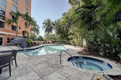 a swimming pool with a table and chairs next to a building at Coconut Grove Retreat 1 bedroom apartment with Bay views in Miami