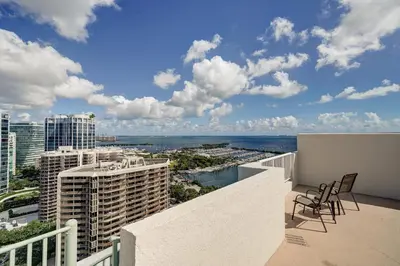 a balcony with chairs and a view of the ocean at Luxury Penthouse with Private Rooftop Terrace in Coconut Grove Hotel in Miami