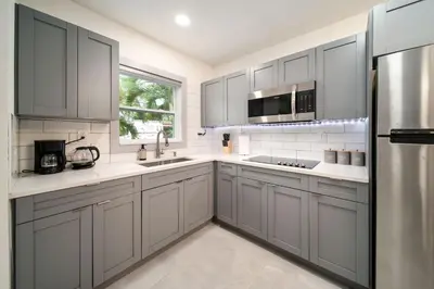 a kitchen with gray cabinets and a stainless steel refrigerator at Modern Apt Near Las Olas Beach in Fort Lauderdale