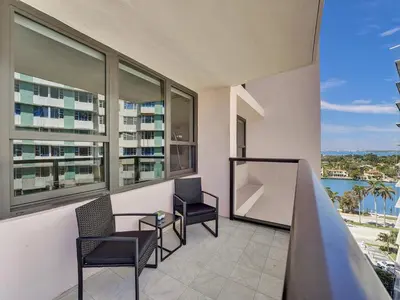 a balcony with two chairs and a table and windows at Cozy Beachfront Condo w Beach Service 1410 in Miami Beach