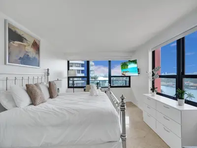 a white bedroom with a large bed and windows at Beach Resort condo 921 in Miami Beach