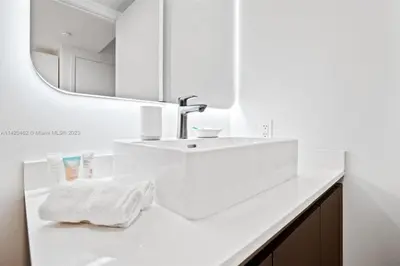 a white bathroom with a sink and a mirror at Ocean View Cozy Studio Pool and Gym in Miami
