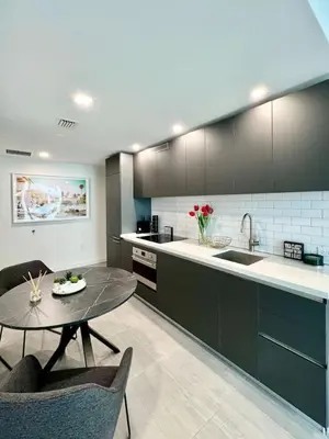 a kitchen with black cabinets and a table with chairs at Ocean view Studio Pool and gym in Miami