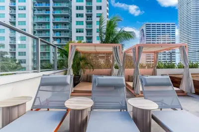 a patio with chairs and tables on a balcony with buildings at Ocean view Studio Pool and gym in Miami